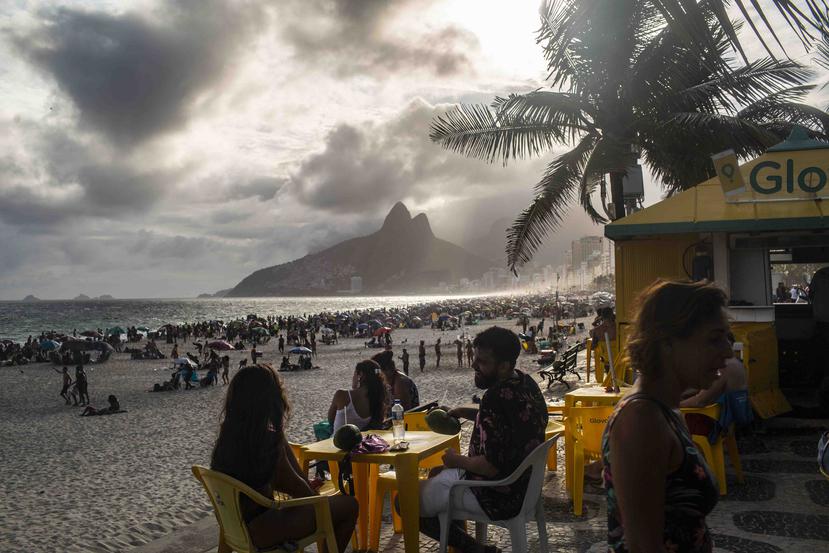 La gente bebe agua de coco mientras disfruta de la tarde en un quiosco playero en Ipanema, Río de Janeiro. (Dado Galdieri/The New York Times)