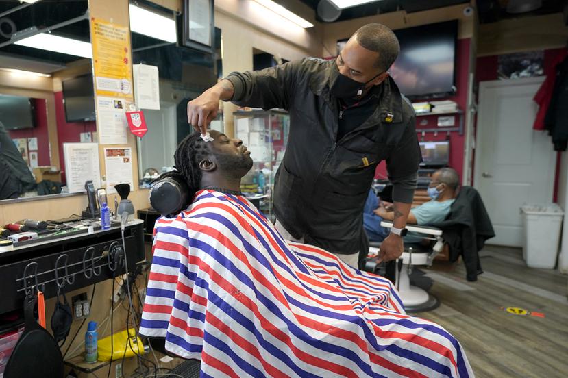 Mike Brown le corta el cabello a Vyron Cox Jr. mientras promueve la vacunación contra el COVID-19 en Hyattsville, Maryland.