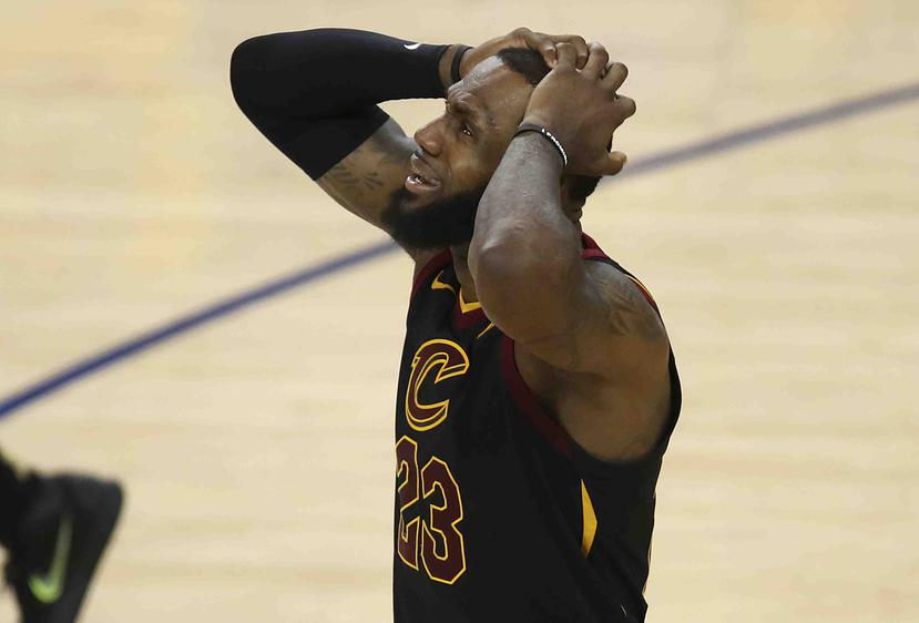 LeBron James, de los Cavaliers de Cleveland, lleva las manos a su cabeza mientras miraba que el marcador le daba la victoria a los Warrrios de Golden State. (AP)