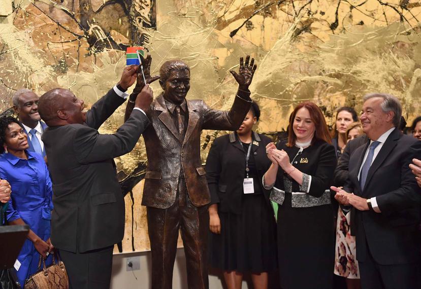 El presidente de Sudáfrica Cyril Ramaphosa coloca la bandera sudafricana en la mano de la estatua del expresidente Nelson Mandela. (EFE / Ángel Weiss)