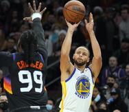 El base de los Warriors de Golden State Stephen Curry lanza el balón sobre el alero de los Suns de Phoenix Jae Crowder.