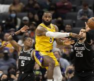 El jugador de los Lakers de Los Ángeles LeBron James pasa el balón mientras los jugadores de los Kings de Sacramento De'Aaron Fox (5) y Alex Len (25) defienden, en la segunda mitad de su juego de NBA en Sacramento, California, el miércoles 12 de enero de 2022. Los Kings ganaron 125-116.