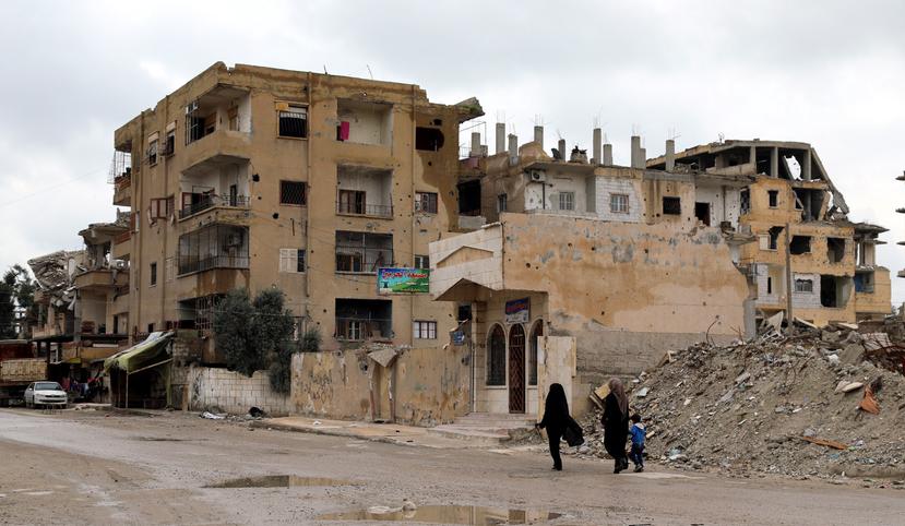 Dos mujeres sirias caminan junto a un niño frente a casas derruidas en Al Raqa (Siria), ciudad que fue la capital de facto de los yihadistas del grupo Estado Islámico.