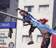 Fanáticos argentinos se subieron a un poste en la conocida avenida 9 de Julio, en Buenos Aires, durante los festejos por la coronación de su equipo en la Copa del Mundo.