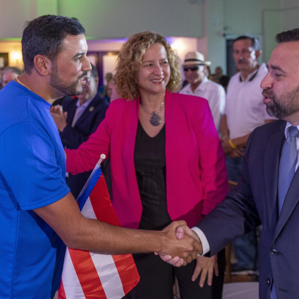 Sara Rosario, al centro, observa a Jean Pizarro ser felicitado por el secretario del Departamento de Estado, Omar J. Marrero Díaz.