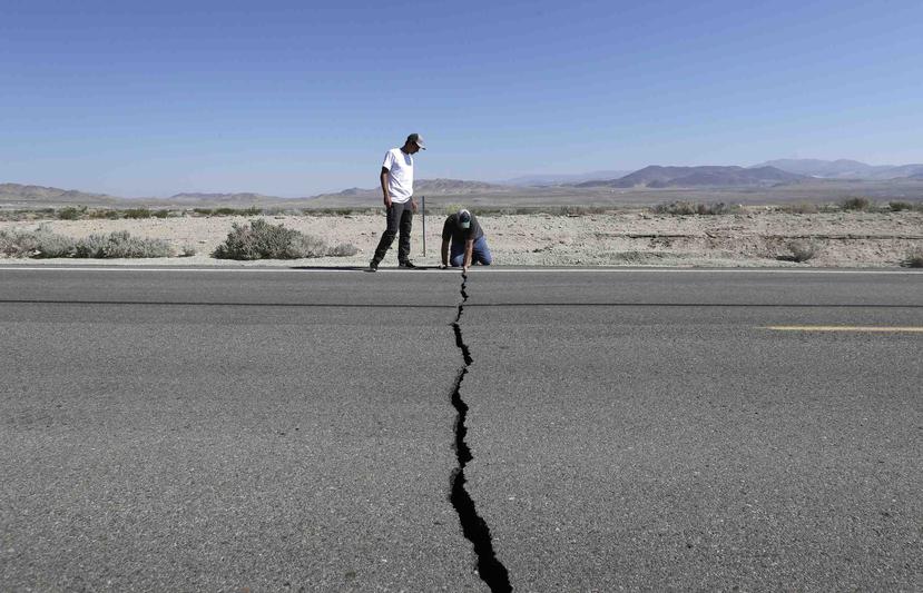 Ron Mikulaco, derecha, y su sobrino Brad Fernandez examinan una grieta causada por un sismo sobre la carretera 178 el sábado en las afueras de Ridgecrest, California. (AP/Marcio Jose Sanchez)