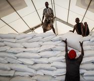 Varios operarios apilan sacos de arroz donados por el Programa Mundial de Alimentos de la ONU.
