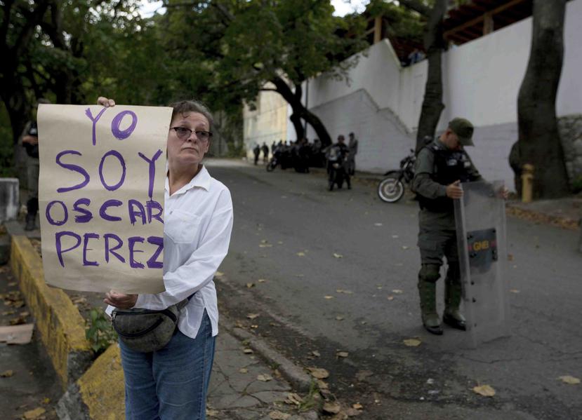 Una mujer que dijo ser partidaria del extinto expolicía Oscar Pérez muestra un cartel en un puesto de control cerca de la morgue donde se encuentra su cadáver en Caracas. (AP)