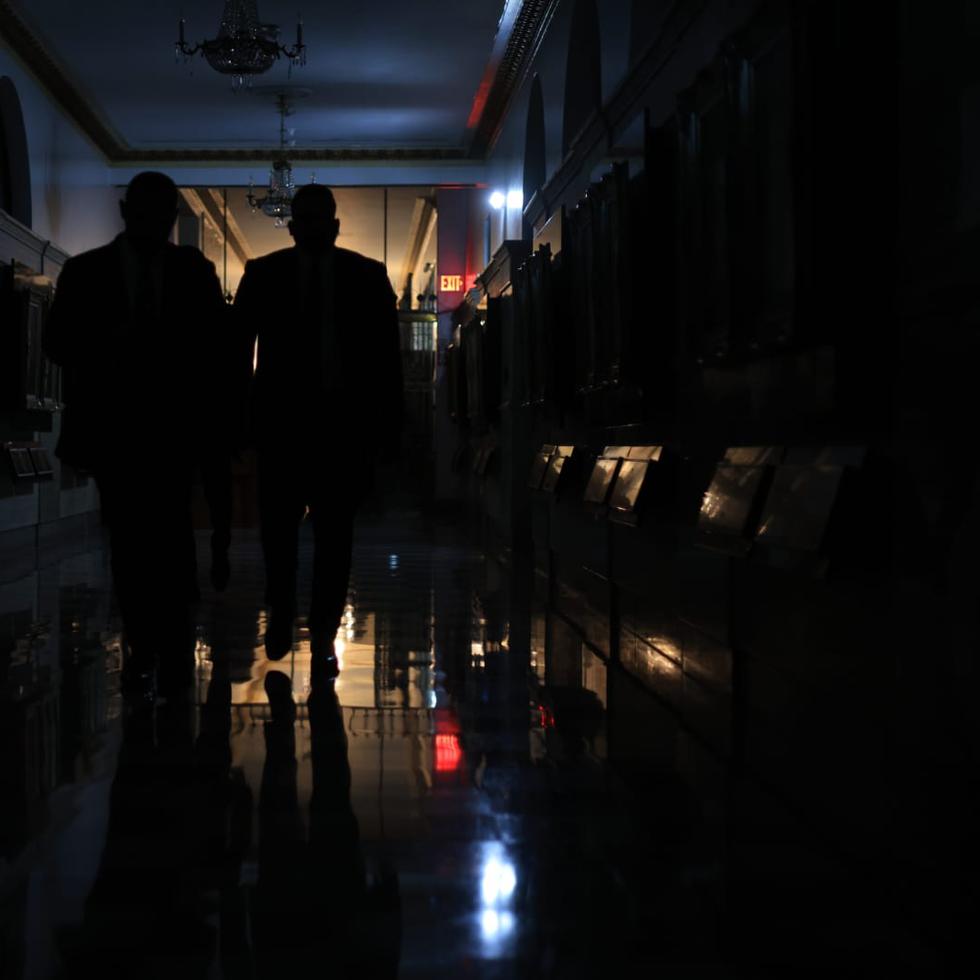 Invitados al mensaje del gobernador en el Capitolio pasan por un pasillo a oscuras.