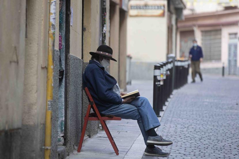 Un hombre lee un libro en las calles de Madrid con una mascarilla. (AP)