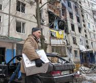 A man carries belongings out of an apartment building hit by shelling in Kharkiv, Ukraine, Tuesday, March 8, 2022. (AP Photo/Andrew Marienko)