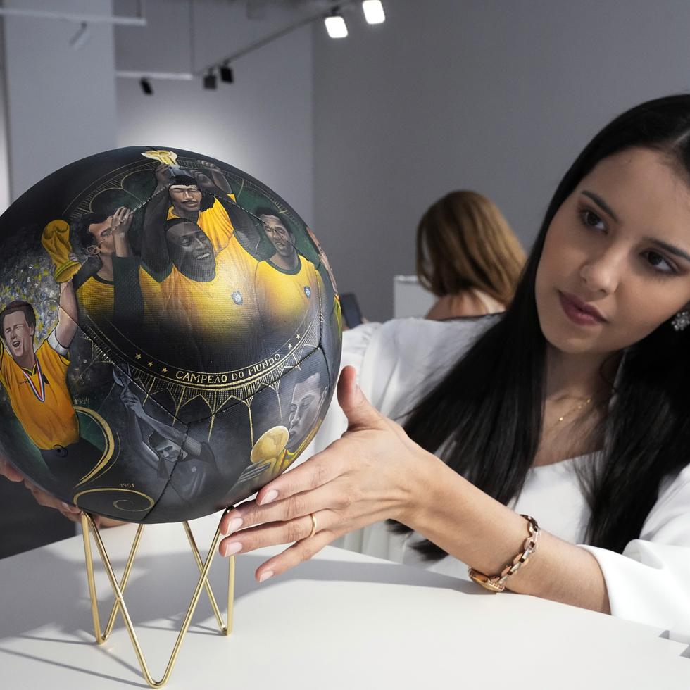 La artista paraguaya Lili Cantero observa uno de los balones que pintó, con la imagen del as brasileño Pelé.