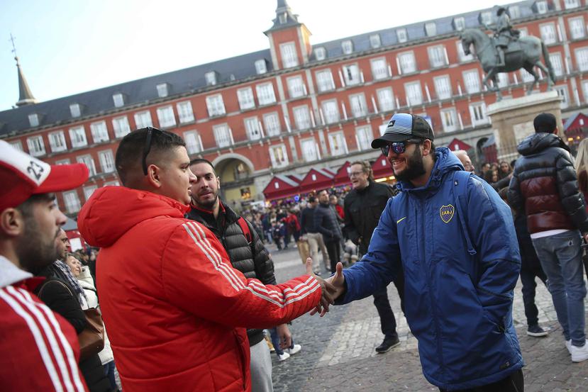 Hinchas de Boca Juniors y River Plate se estrechan la mano al encontrarse en la Plaza Mayor de Madrid. (AP)