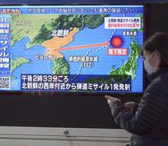 Una mujer camina frente a un televisor que muestra un programa de noticias sobre el lanzamiento de un misil de Corea del Norte, el 24 de marzo de 2022, en Tokio.