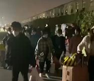 En esta imagen extraída de un video y publicada por Hangpai Xingyang, gente con maletas sale de un complejo de Foxconn en Zhengzhou, en la provincia central china de Henan.