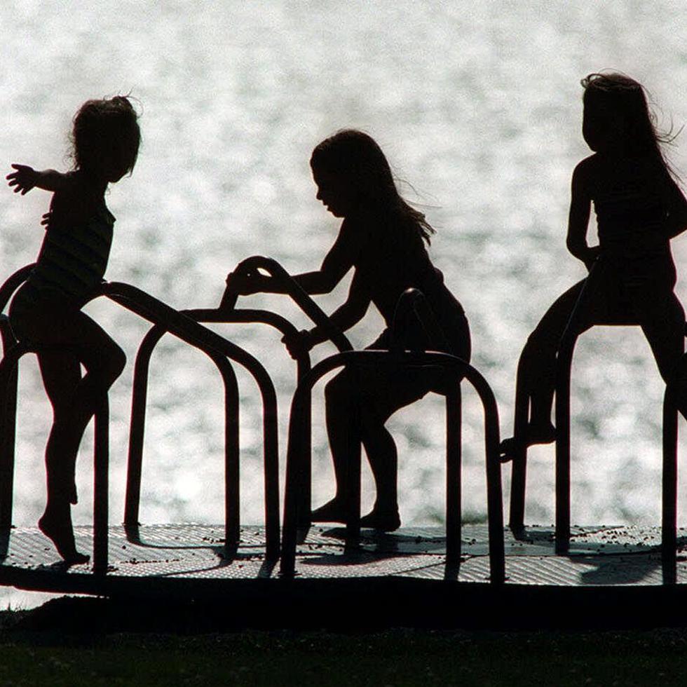 A group of young girls playing on a playground merry-go-round Monday, Aug. 7, 2000, are silhouetted on High Cliff Beach at High Cliff State Park, in Sherwood, Wis. (AP Photo/The Post-Crescent, Dan Powers) TEMAS PARQUE MECEDORA PLAYGROUND COLUMPIO