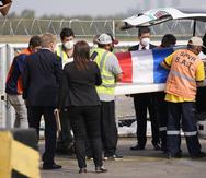 Trabajadores del aeropuerto retiran un ataúd cubierto con una bandera con los restos de Leidy Luna Villalba en el aeropuerto Silvio Pettirossi en Luque, Paraguay.