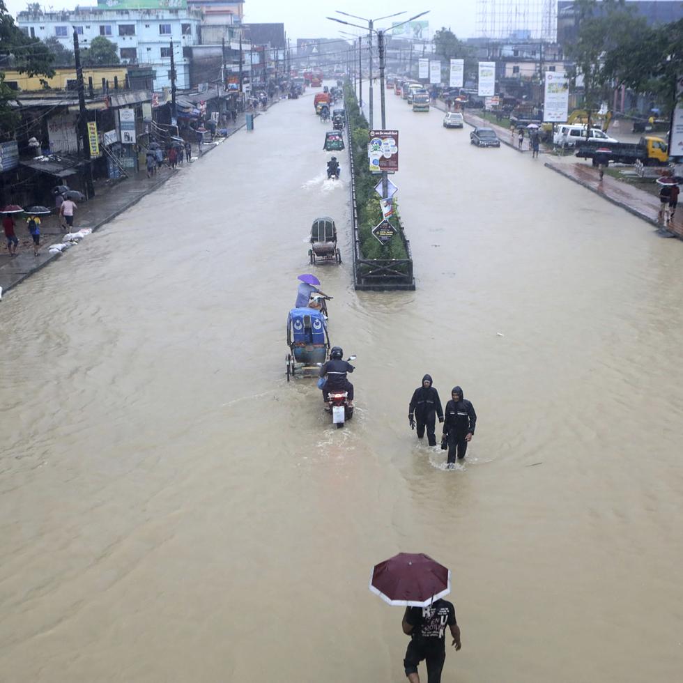 Personas caminando a través de un área inundada por Sylhet, Bangladesh.