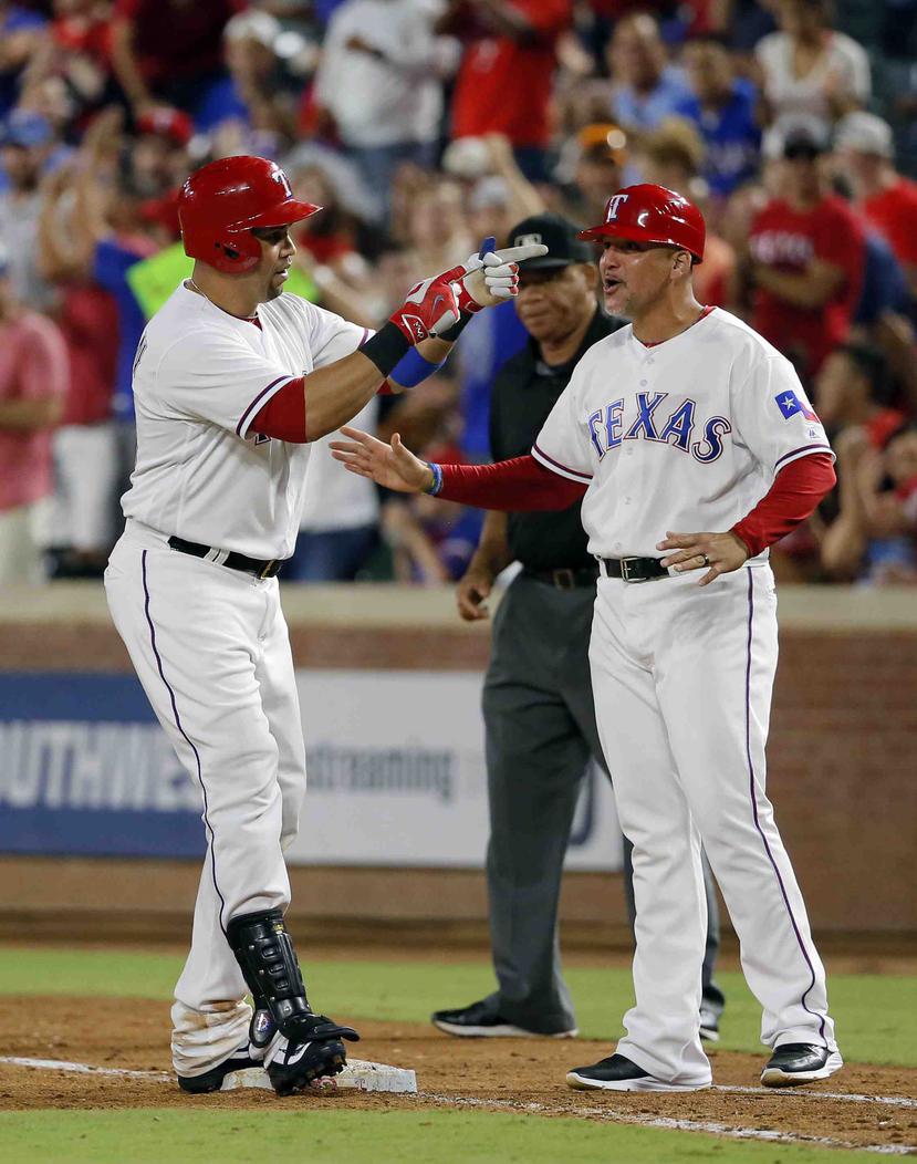 Héctor "Boliche" Ortiz (derecha) es coach de primera base de los Rangers de Texas. (AP)