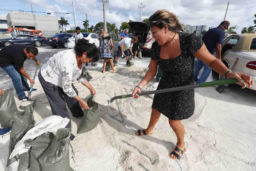 Georgia Bernard (derecha) y Ana Pérez, junto a otros residentes, llenan sacos de arena para llevárselos a casa antes de la llegada del potente huracán Dorian, el 30 de agosto de 2019, en Hallandale Beach, Florida. (AP/Wilfredo Lee)