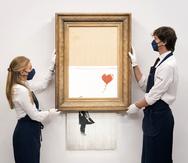 Manipuladores de arte sostienen "Love is in the Bin" de Banksy en la casa de subastas Sotheby's en Londres.