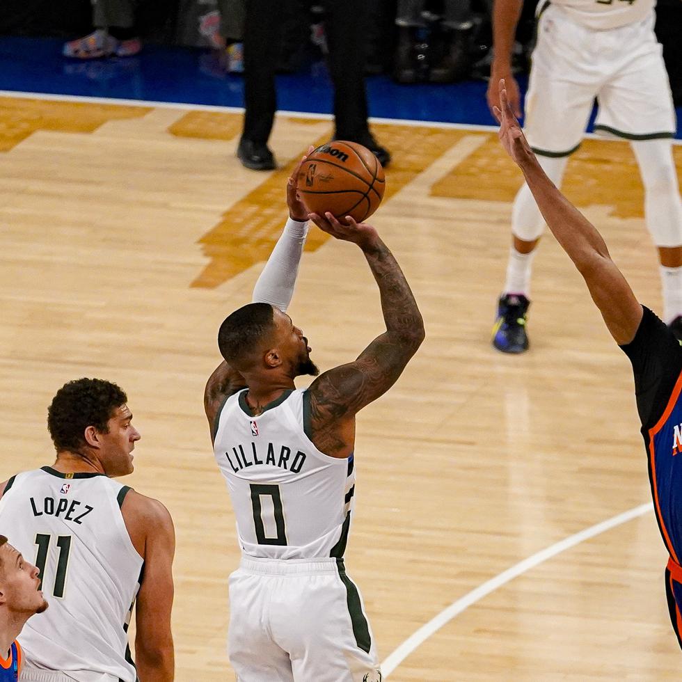 El base de los Bucks de Milwaukee Damian Lillard lanza el balón sobre el alero de los Knicks de Nueva York Taj Gibson en el encuentro de la NBA del sábado 23 de noviembre del 2023.