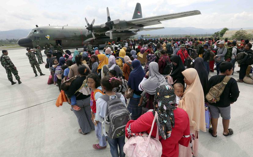 Un grupo de personas espera para embarcar en un avión de carga de la Fuerza Aérea en el aeropuerto Mutiara Sis Al-Jufri para salir de la ciudad de Palu, afectada por un sismo y un posterior tsunami, en el centro de la isla de Célebes, en Indonesia. (AP)
