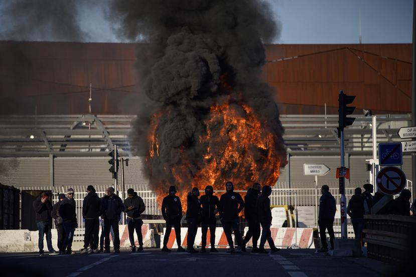 Trabajadores portuarios de pie ante una barricada en llamas junto al puerto de Marsella, en el sur de Francia, el miércoles 22 de marzo de 2023.