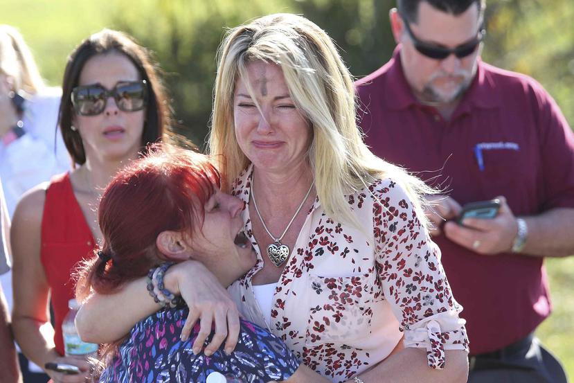 Dos mujeres lloran tras el reporte de un tiroteo en la Escuela Secundaria Marjory Stoneman Douglas de Parkland, Florida. (AP)