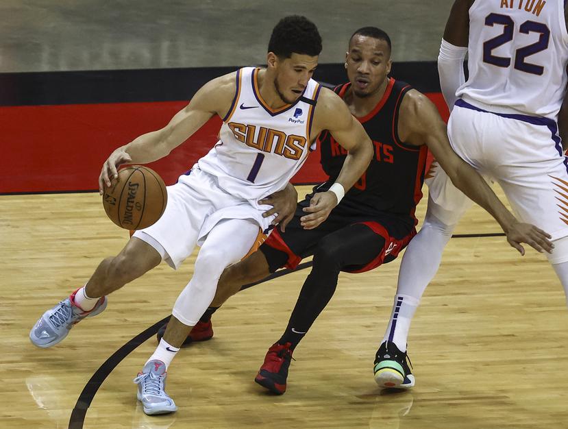 El base de los Suns de Phoenix Devin Booker controla el balón mientras lo defiende Avery Bradley de los Rockets de Houston en el encuentro.
