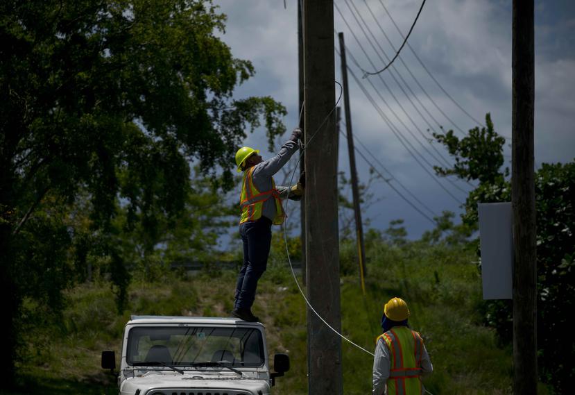 Trabajadores de la brigada de reparaciones eléctricas retiran viejos cables de un poste en San Germán. (AP)