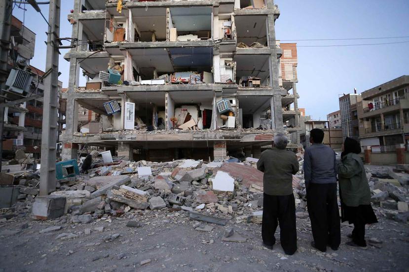 Tres personas observan un edificio que colapsó tras el terremoto. (AP)