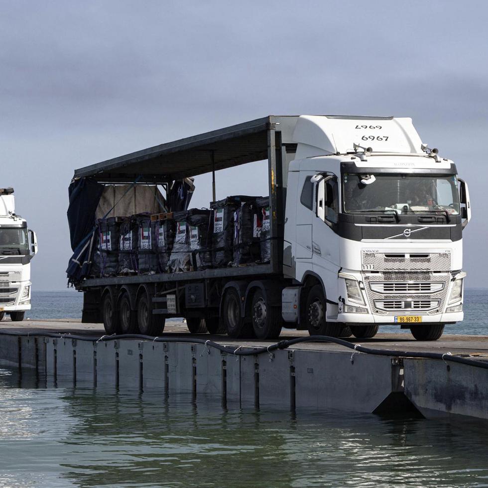 Camiones cargados de ayuda humanitaria cruzan el muelle flotante Trident antes de llegar a la playa en la Franja de Gaza