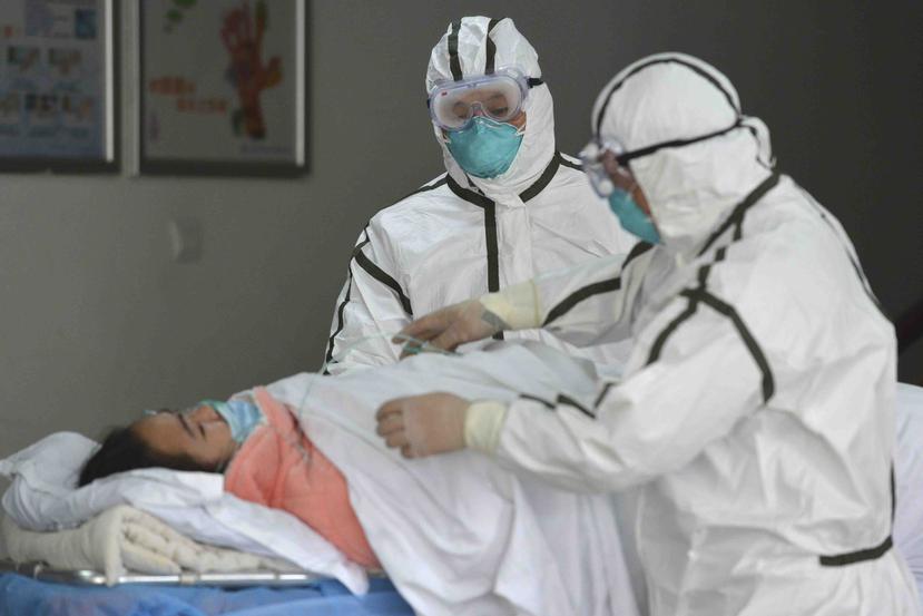 Personal sanitario provisto con trajes protectores traslada a una paciente infectada con coronavirus a un pabellón de aislamiento en China. (AP)