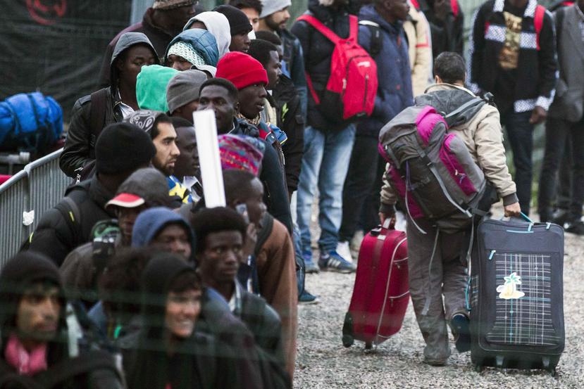 Varios migrantes esperan una cola en el centro de recepción de corta estancia. (Agencia EFE)