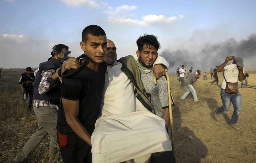 Manifestantes palestinos cargan a un hombre herido cerca de la frontera de la Franja de Gaza con Israel. (AP)