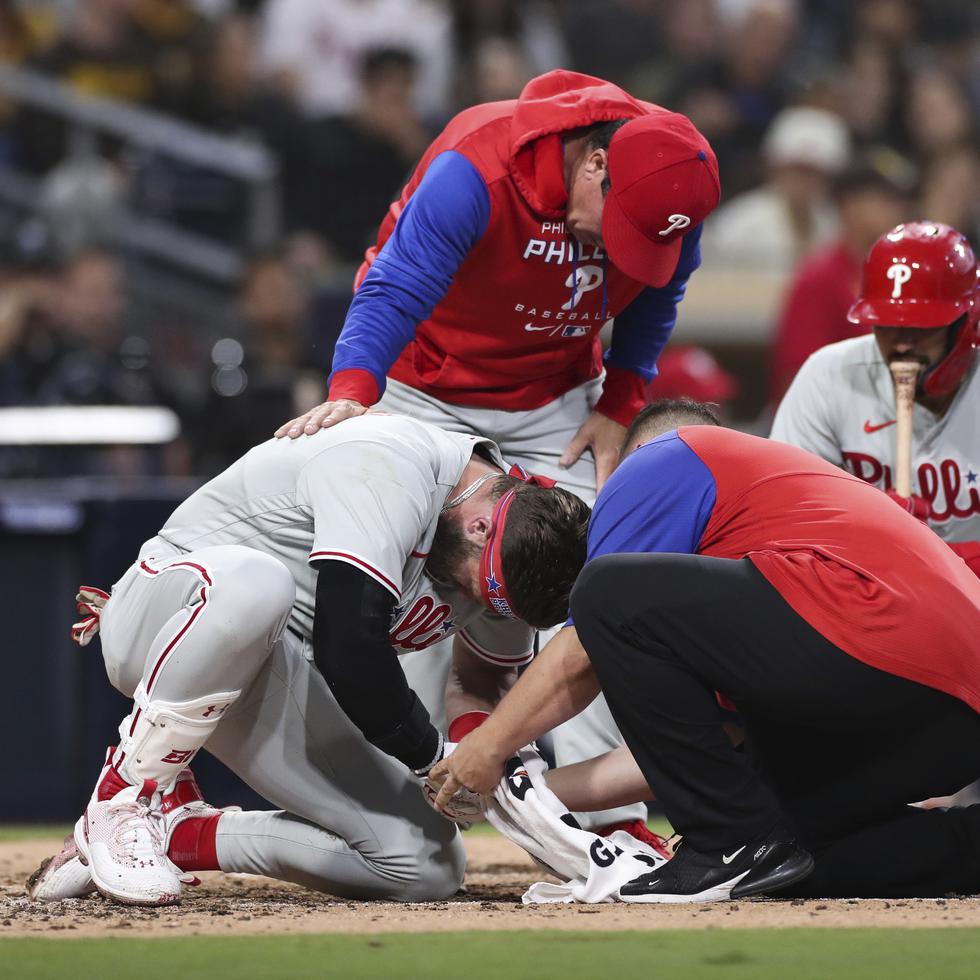 Bryce Harper (izquierda) recibe atención médica luego de ser alcanzado por una pelota en el cuarto inning de su juego de béisbol contra los Padres de San Diego, el 25 de junio de 2022.