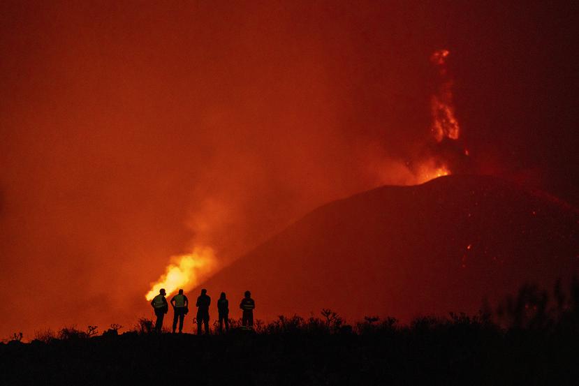 Agentes de policía y personal de emergencias contemplan el flujo de lava de un volcán que continúa en erupción en La Palma, Islas Canarias.