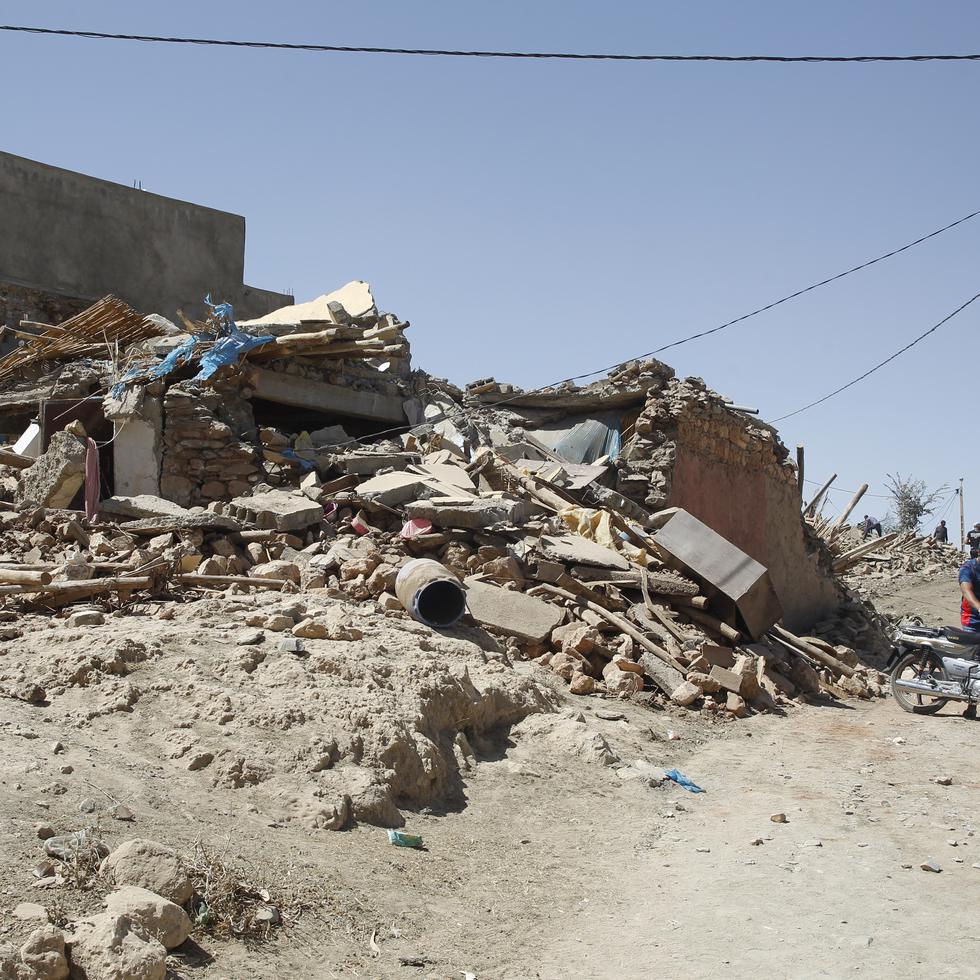 Varias personas caminan entre los escombros en la aldea de Tafagajt, en Marruecos, cerca del epicentro del devastador terremoto de magnitud 6.8.