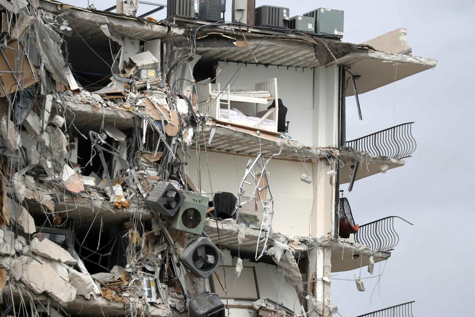 Artículos, consolas de acondicionadores de aire y camas quedan expuestas tras el colapso parcial del condominio Champlain Towers South en Miami.