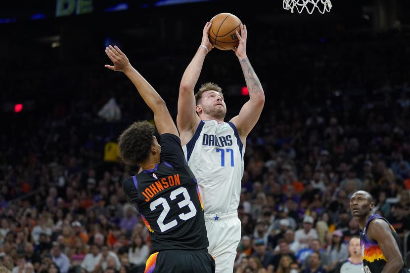 Luka Doncic (77), de los Mavericks de Dallas, ataca la canasta sobre Cameron Johnson (23), de los Suns de Phoenix, durante la segunda mitad del Juego 7 de las semifinales de la Conferencia Oeste.