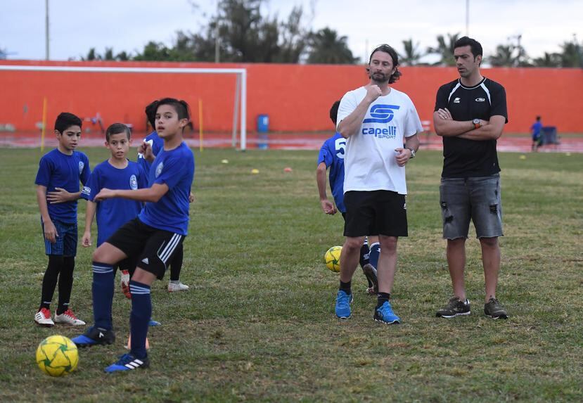 Tiago  Calvano (derecha) y Davide Corti observan un entrenamiento de varios niños del San Juan Fútbol Club.