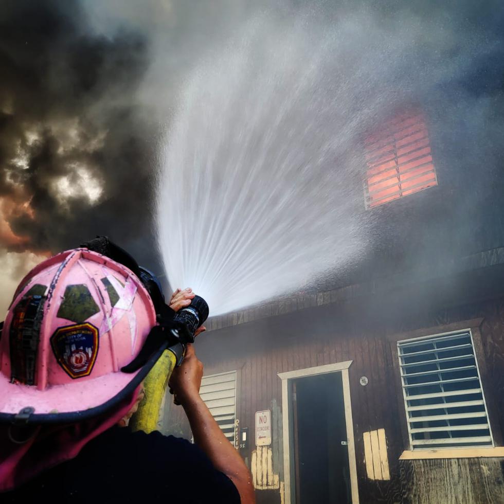 Un bombero intenta controlar el incendio de una de las casas afectadas de las barrida Figueroa, en Santurce.