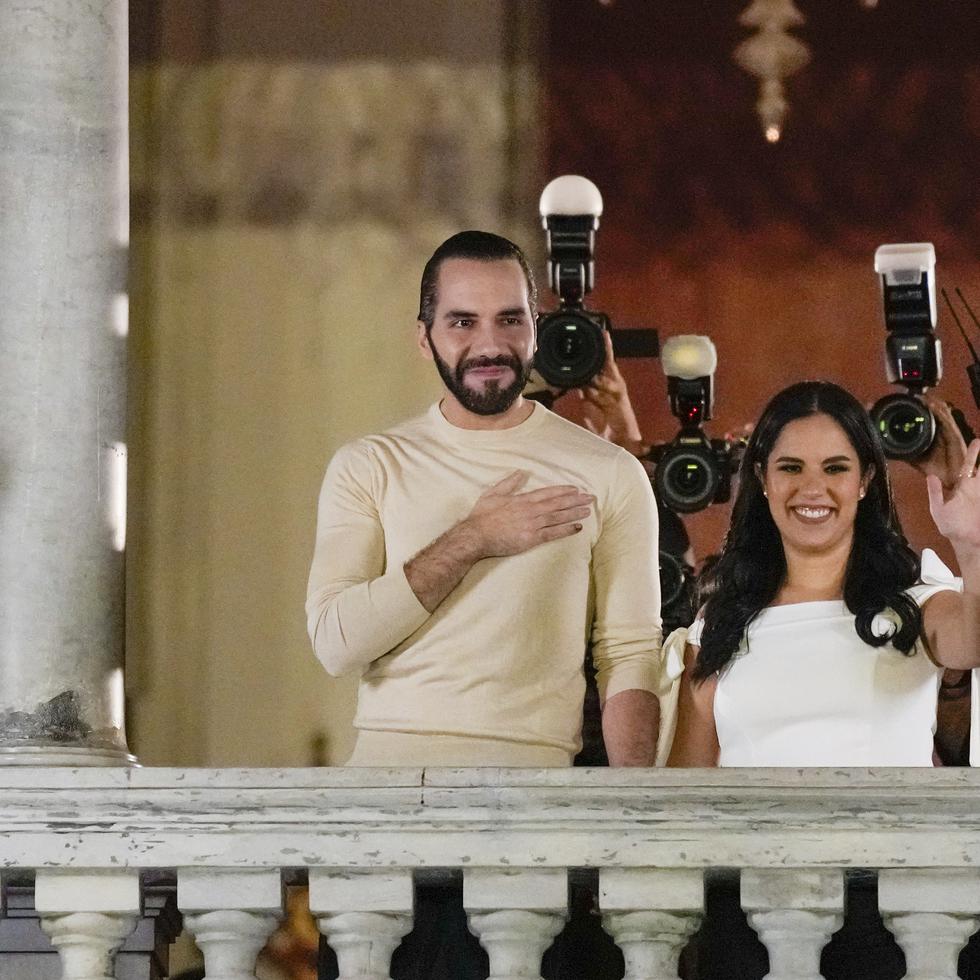 El Salvador President Nayib Bukele, left, accompanied by his wife Gabriela Rodriguez, wave to supporters from the balcony of the presidential palace in San Salvador, El Salvador, after polls closed for general elections on Sunday, Feb. 4, 2024. (AP Photo/Moises Castillo)