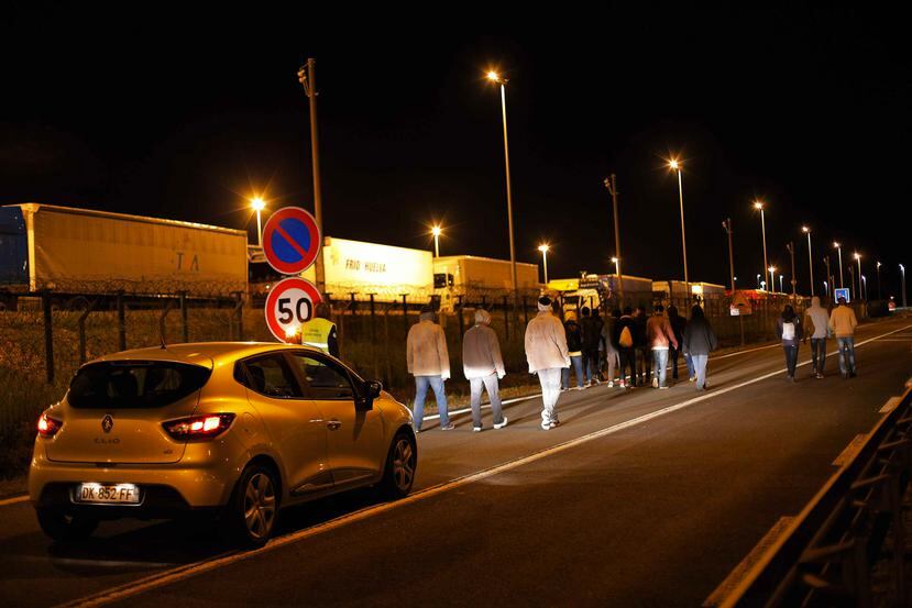 Un auto de seguridad de Eurotunnel sigue a un grupo de migrantes en Calais, Francia.