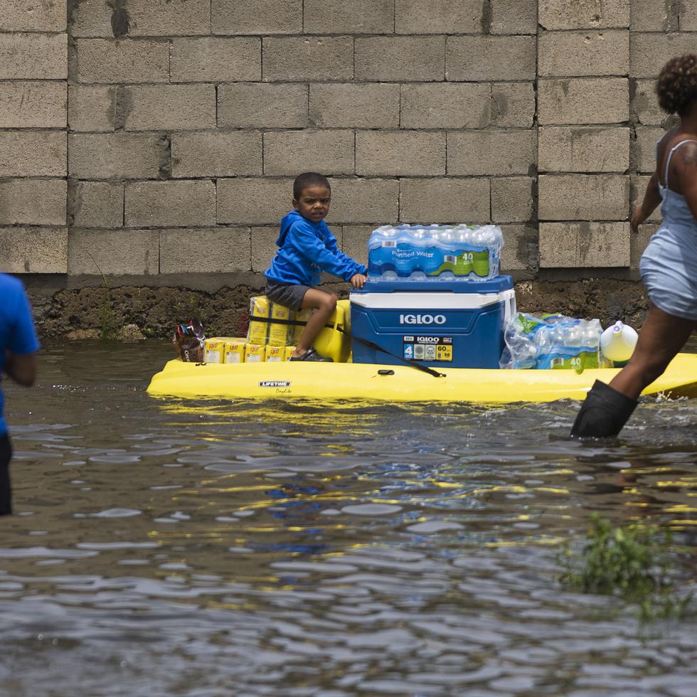 Canovanas , Puerto Rico, Septiembre 20 , 2022 - MCD -  FOTOS para ilustrar una historia sobre los estragos del paso del huracán Fiona en Loíza . EN LA FOTO una vista de la inundación ( inundacion ) en el barrio Villa Santos en Loiza - un hombre transportaba unos paquetes de botellas de agua y a un niño encima de un kayak .   
FOTO POR:  tonito.zayas@gfrmedia.com
Ramon " Tonito " Zayas / GFR Media
