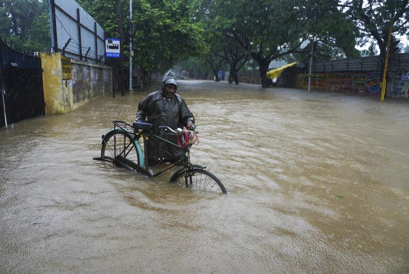 Un hombre empuja su bicicleta por una calle inundada en Chennai, en el estado sureño indio de Tamil Nadu.