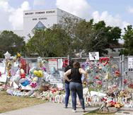 Dos personas observan un altar improvisado en memoria de las víctimas del tiroteo en la Escuela Secundaria Marjory Stoneman Douglas en Parkland, Florida. (AP)