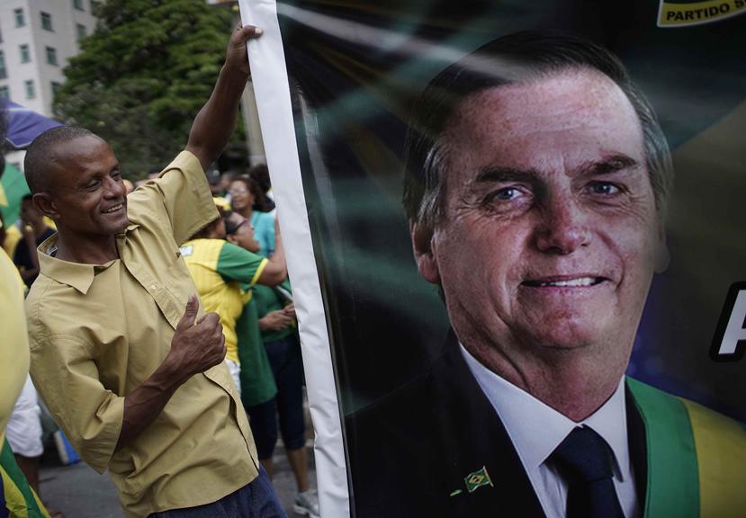 Un partidario del presidente brasileño Jair Bolsonaro ayuda a cargar una imagen gigante del mandatario durante una marcha en apoyo a él, en la playa de Copacabana en Río de Janeiro, Brasil, el domingo 26 de mayo de 2019. (AP/Silvia Izquierdo)
