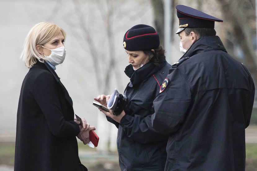 En Moscu una mujer presenta sus documentos a dos policías. (AP)